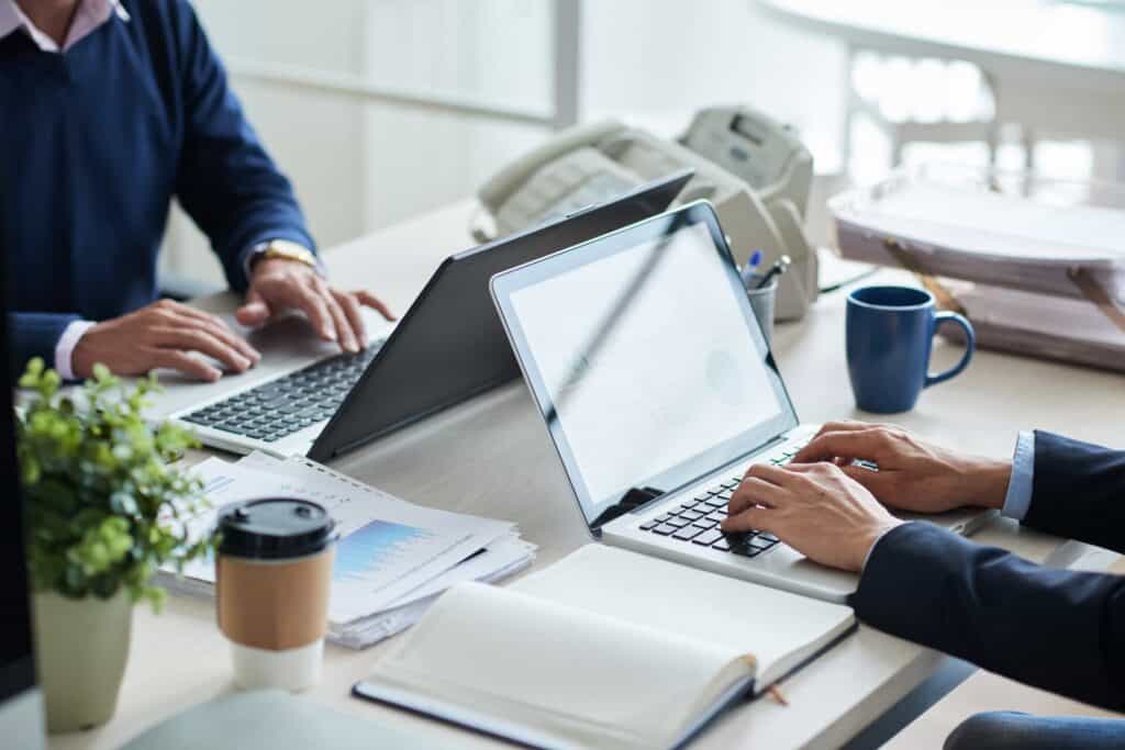 Foto: To personer som sitter mot hverandre med hver sin laptop og skriver.