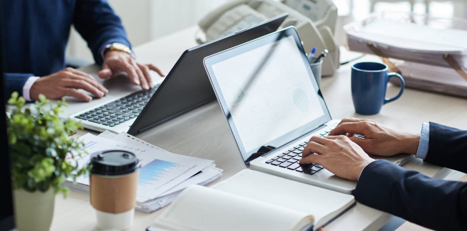 Foto: To personer som sitter mot hverandre med hver sin laptop og skriver.